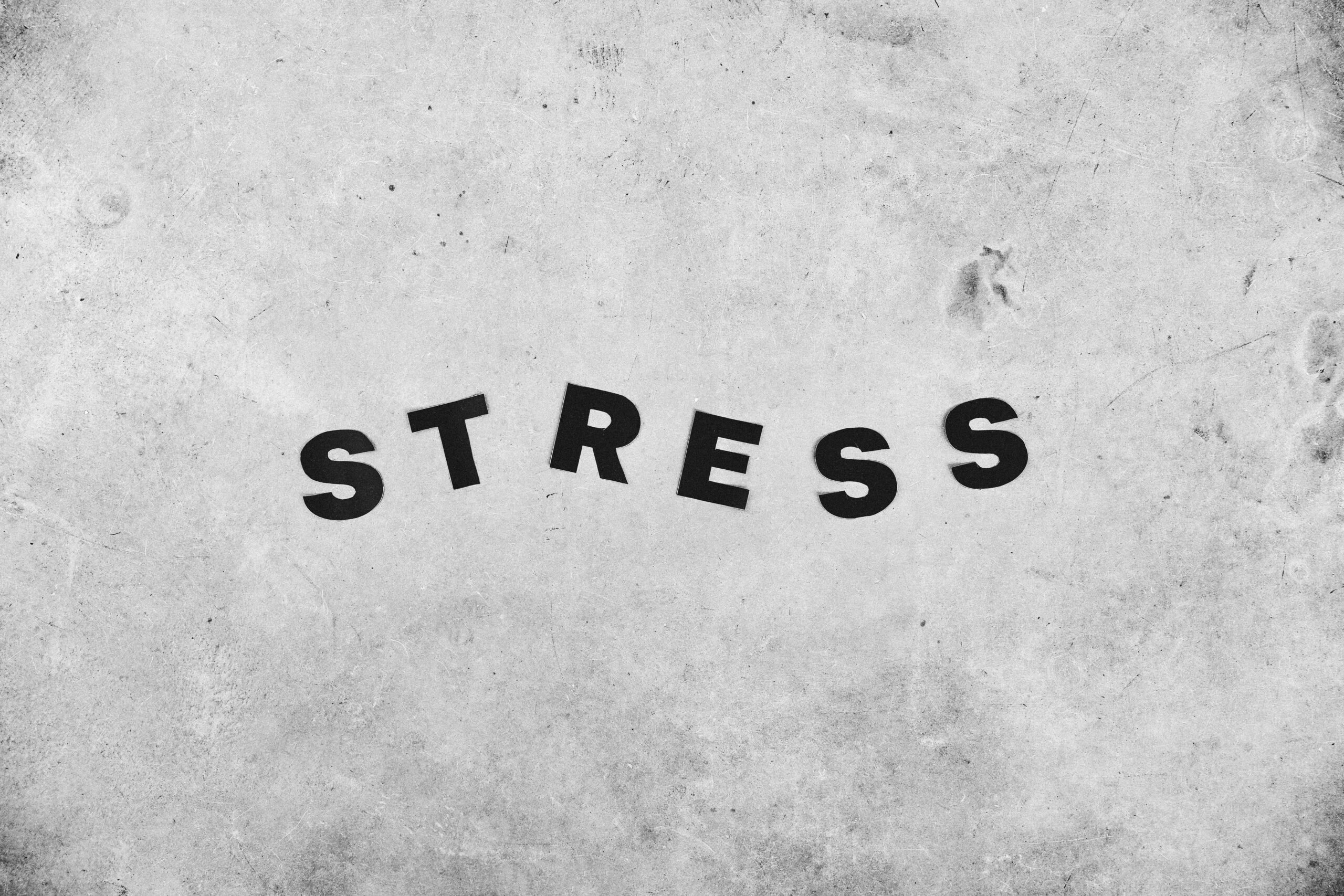 Imagem com fundo cinza e a palavra “stress”, representando estresse mental e ansiedade.